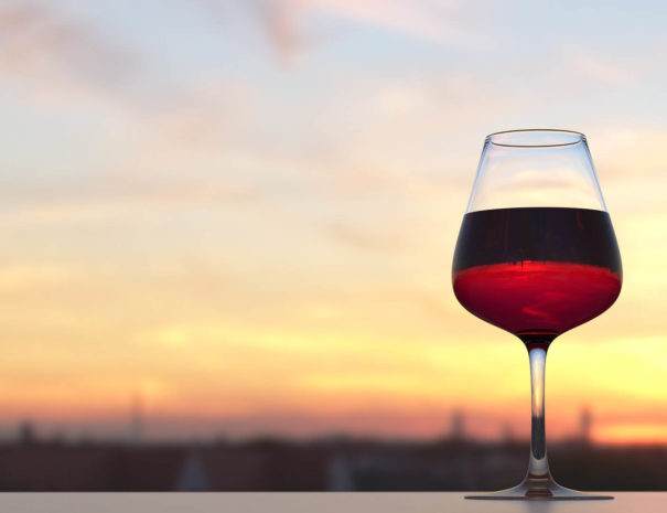 Copa de vino en una azotea con vistas a una puesta de sol en Barcelona