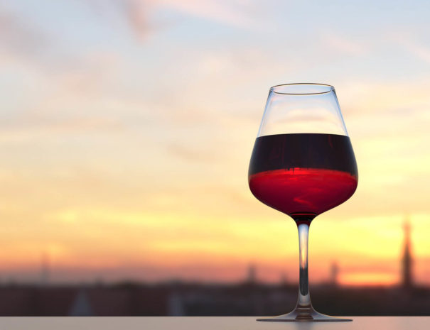 Glass of wine on a rooftop with a sunset view